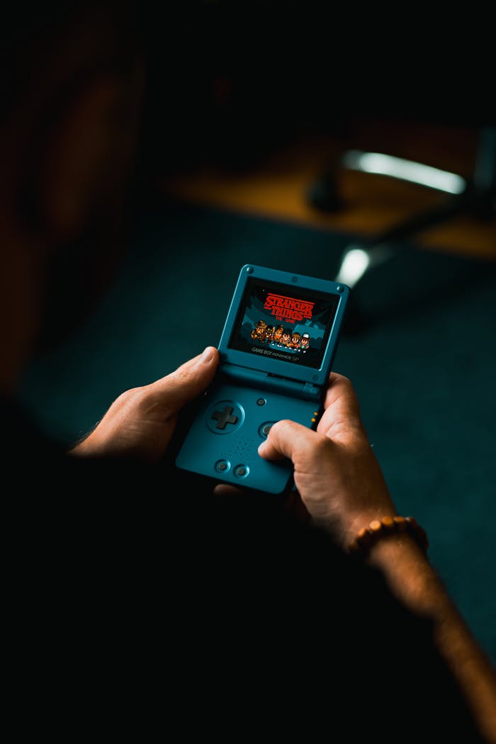 why-choose-us Close-up of individual holding a retro handheld gaming device, playing a classic video game indoors.